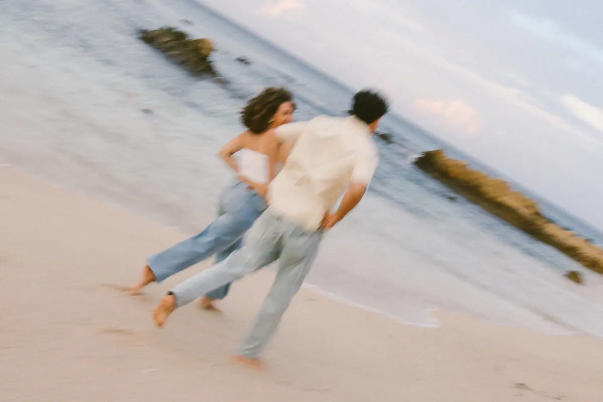 The couple running along the shore, blurred with motion