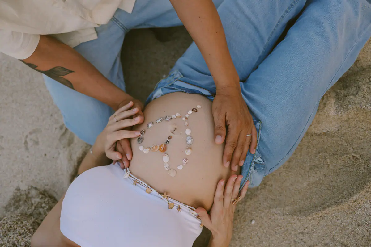Small shells arranged on her belly, his hands and hers around them