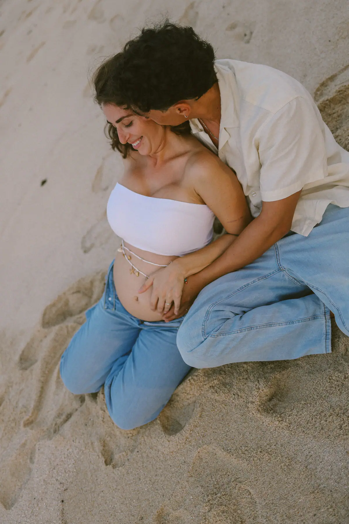 The couple lying in the sand, photographed from above, both smiling