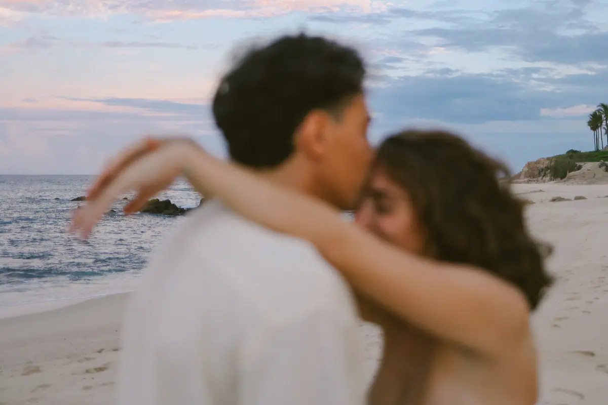 A kiss on the forehead by the sea, soft with motion