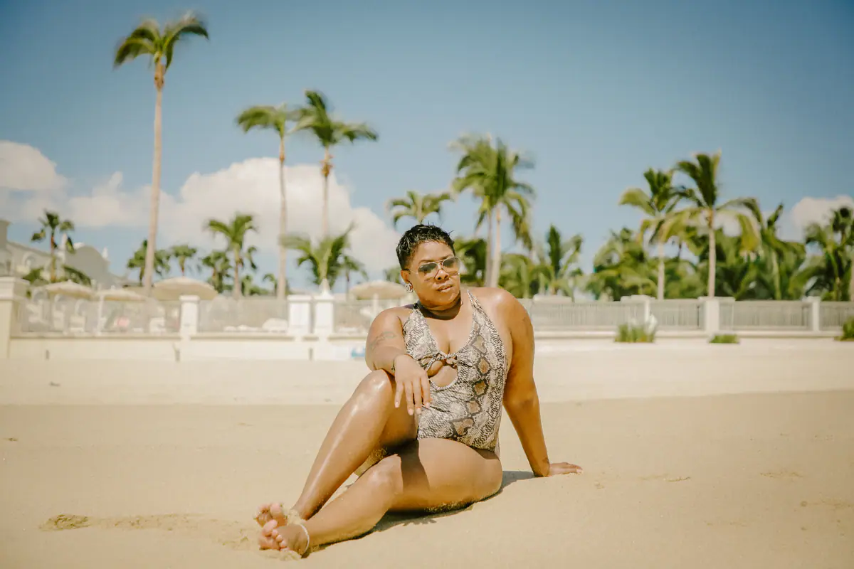 Portrait of a woman sitting on the sand with palm trees behind her