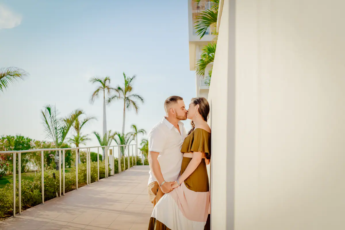 A couple kissing on a path lined with palm trees