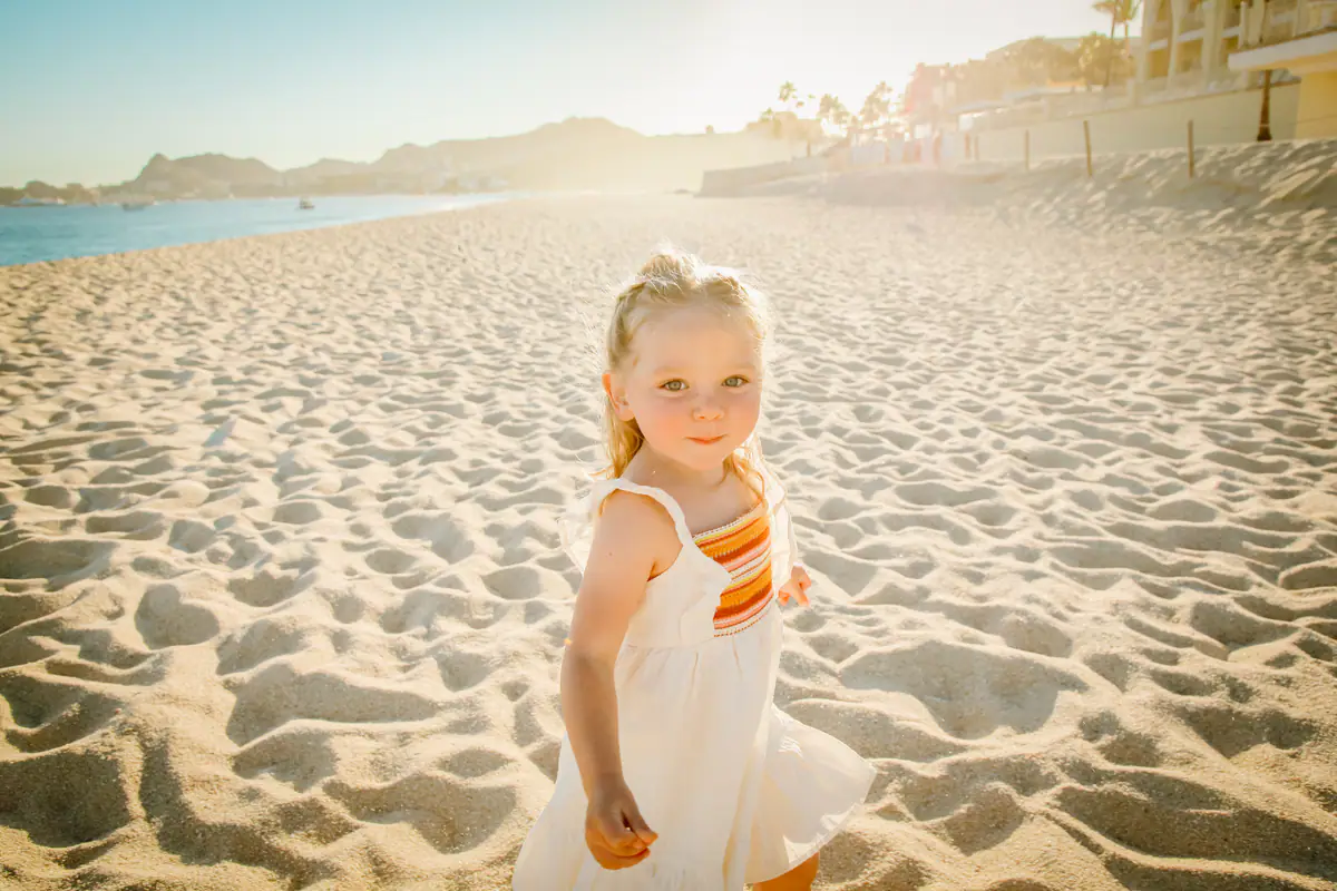A little girl on the sand looking at the camera